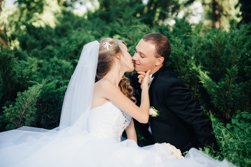 Bride sit together with groom on green grass park 