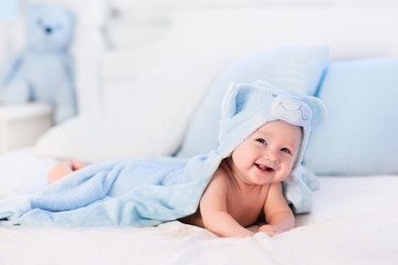 Fototapeta na wymiar Baby boy in blue towel on white bed