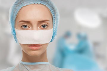 Close-up of bandaged face after cosmetic operation in surgery room interior