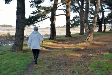 Une dame agée marche en bordure de mer près de Plougrescant