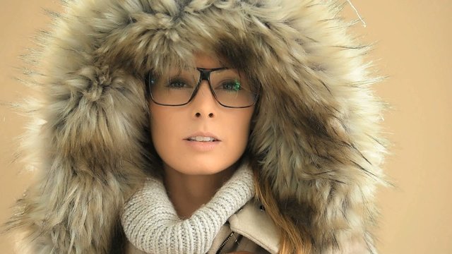Woman with eyeglasses wearing fur hood, isolated