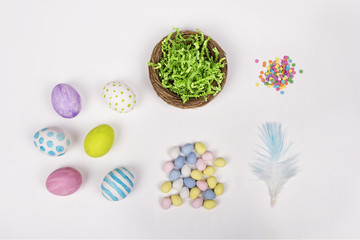 Easter eggs, basket, and candy on a white background