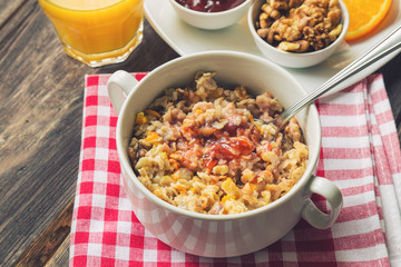 Oatmeal with walnuts, orange peel and jam for breakfast