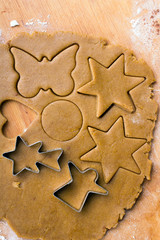 Cookies forms and gingerbread dough on wooden pastry board