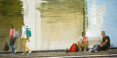 Junge Menschen spiegeln sich im Wasser eines großen Brunnen