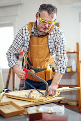 Carpenter working on a hand saw cutting boards in his workshop