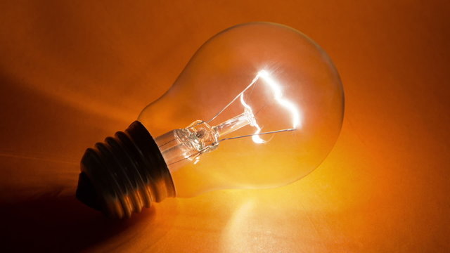 Blinking ligh tbulb  on the yellow background. Note that lamp is not connected to the  energy source.