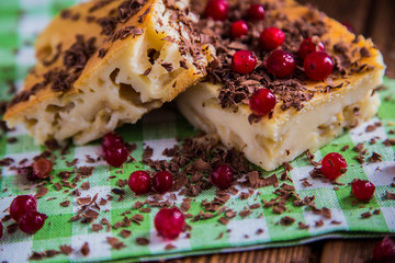Apple pie on  napkin and wood surface with chocolate, cranberries