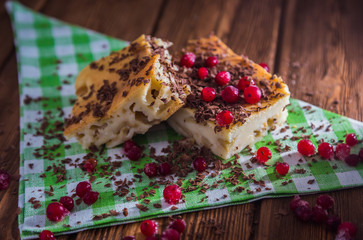 Apple pie on  napkin and wood surface with chocolate, cranberries