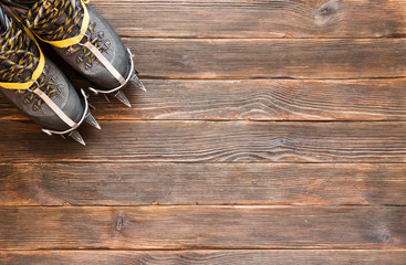 trekking shoes with crampons on dark wooden background, top view