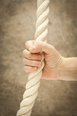 Image of hands and a rope on the abstract background