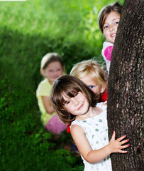 Happy children hideing behind the tree in forest