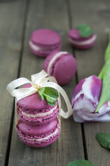 Sweet crimson french macaroons tied with ribbon and tulip on dark wooden background