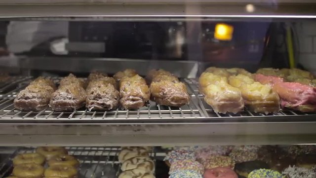 Slow, wide tracking shot of donuts in a bakery