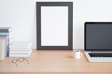 Blank picture frame on wooden table with books, cup of coffee an