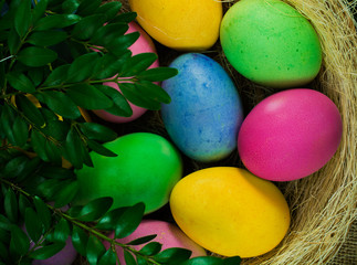 Fototapeta na wymiar Colorful Easter eggs on hay in the wicker basket