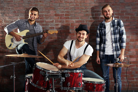 Musicians playing the drums on brick wall background