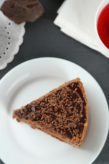Sliced chocolate cake on plate, on wooden table  background