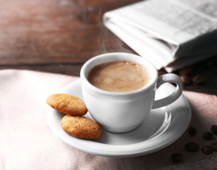 Cup of coffee, cookie and newspaper on wooden table background