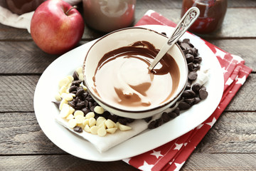 Melted chocolate in bowl, on wooden background