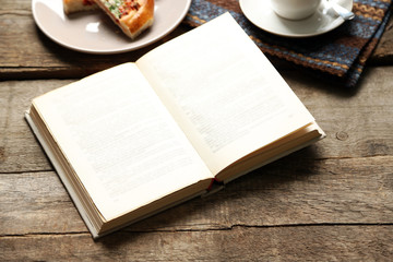 Open book and snack on wooden table background