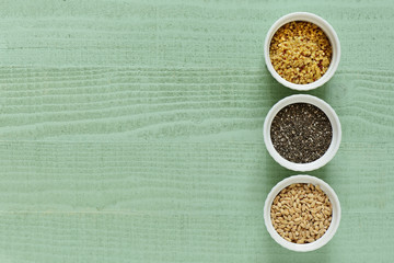 semi di chia orzo boulgur e quinoa su sfondo legno verde pastello