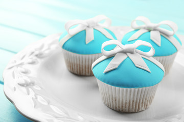 Tasty cupcakes with bow on color wooden background