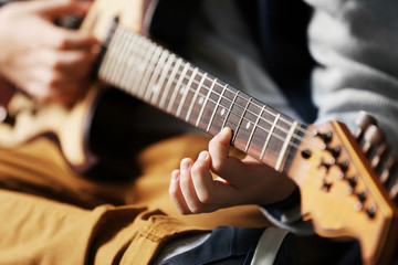 Fototapeta na wymiar Cute little boy playing guitar on brick wall background