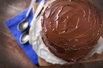 Chocolate cake with two spoons and blue tablecloth on a wooden boards background