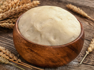Fresh dough on bowl and ears the table.