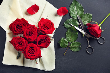 Fresh red roses buds in shape of heart with linen fabric on black textured background