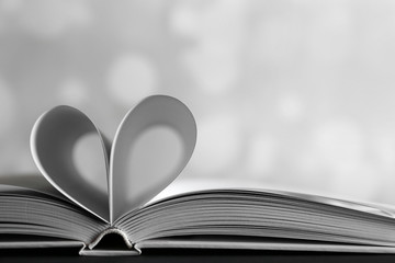 Sheets of book curved into heart shape on unfocused gray background