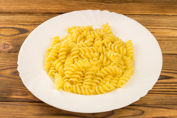 Italian pasta fusilli in plate on wooden table