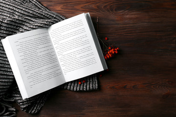 An open book, rowan berries and a blanket on the wooden background