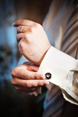 man puts cufflinks on sleeve white shirts