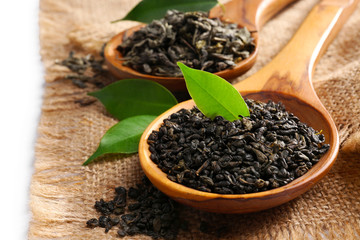 Dry tea with green leaves in wooden spoons, close up