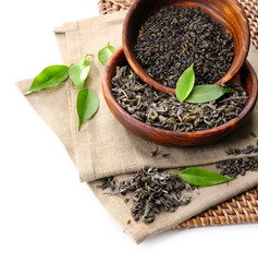 Dry tea with green leaves in wooden utensil, isolated on white