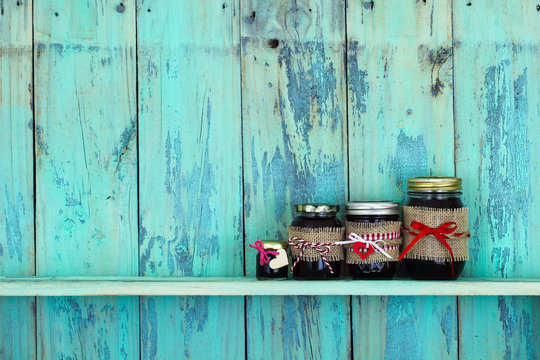 Jars of fruit jelly on rustic teal blue wood shelf