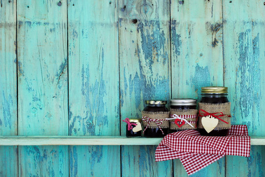 Jars of fruit jam and red checkered linen on rustic teal blue wood shelf
