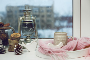 Fototapeta na wymiar Cup of hot drink in on the windowsill in living room. Comfortable winter weekend or holidays at home