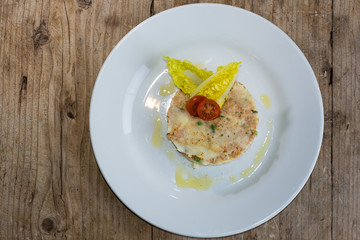 Crab pie from above. French restaurant prepared dish with crab meat, potatoes, peas, herbs and salad
