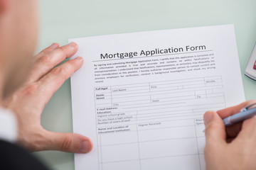 Person Hand Over Mortgage Application Form