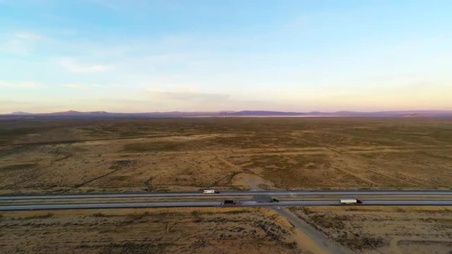 Trucks motorhomes and cars driving on Interstate 40 in the Mojave desert with barren dry  hostile drought scarred desert landscape  as  4k aerial stabilized flying GoPro Hero4 camera shows wide view 