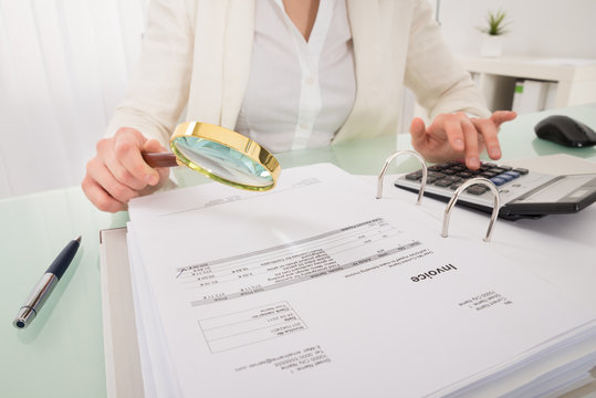 Close-up Of Businesswoman Checking Bill With Magnifying Glass