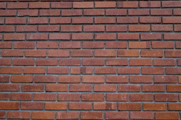 A wall of old red brick with aged different color. The crack and some wreckage can be found all over the wall. Vintage