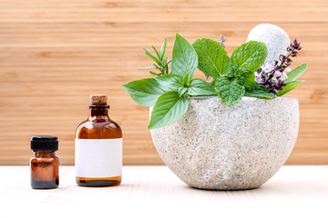 Alternative health care fresh herbs basil ,sage ,rosemary, mint and essential oil with mortar on wooden background.