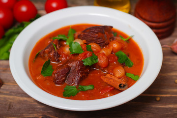 National Greek dish stifado with beef, tomatoes and onions, stewed in red wine with Herbs on a wooden background, horizontal