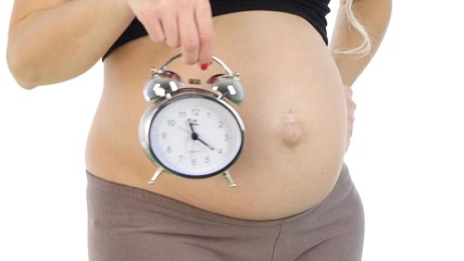 Pregnant woman's belly with an alarm clock, white, closeup - Powered by Adobe