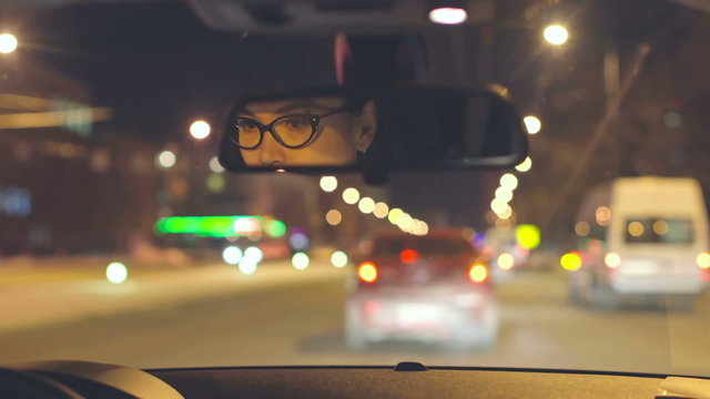Woman driving her car and her face reflected in rear view mirror