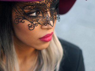 Spring outfit - portrait of a young pretty woman with granny hairstyle, wearing  Marsala sweater, shoes and hat, black jacket and skirt, with a black mask, in Venice.